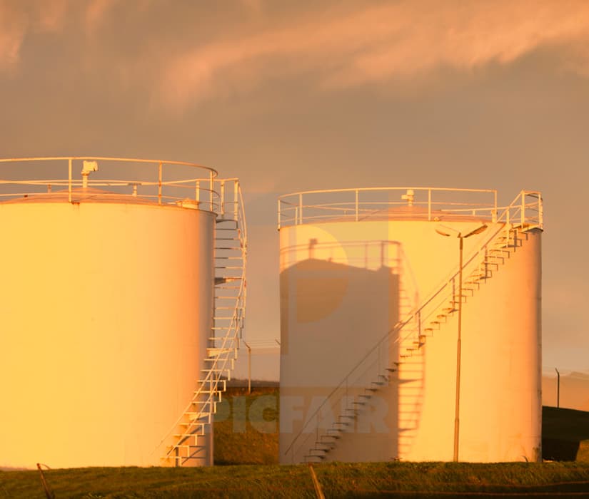 Industrial oil storage tanks at sunset